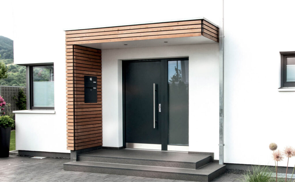 Moderne Eingangstür in Anthrazit mit Seitenteil aus Glas, weißer Putzfassade und Holzverkleidung am überdachten Eingangsbereich